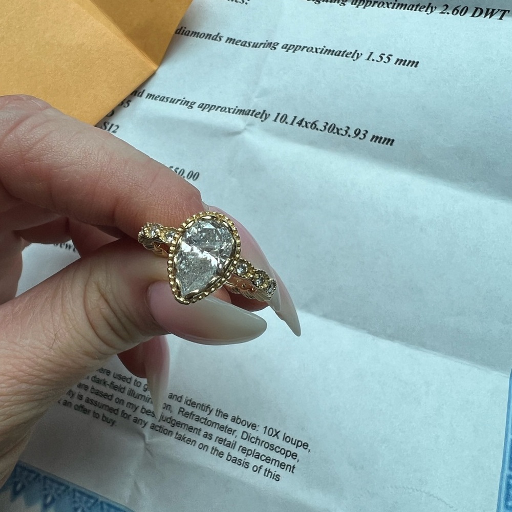 2.6 karat pear shaped diamond ring. Has 12 small diamonds on bad. 14k gold